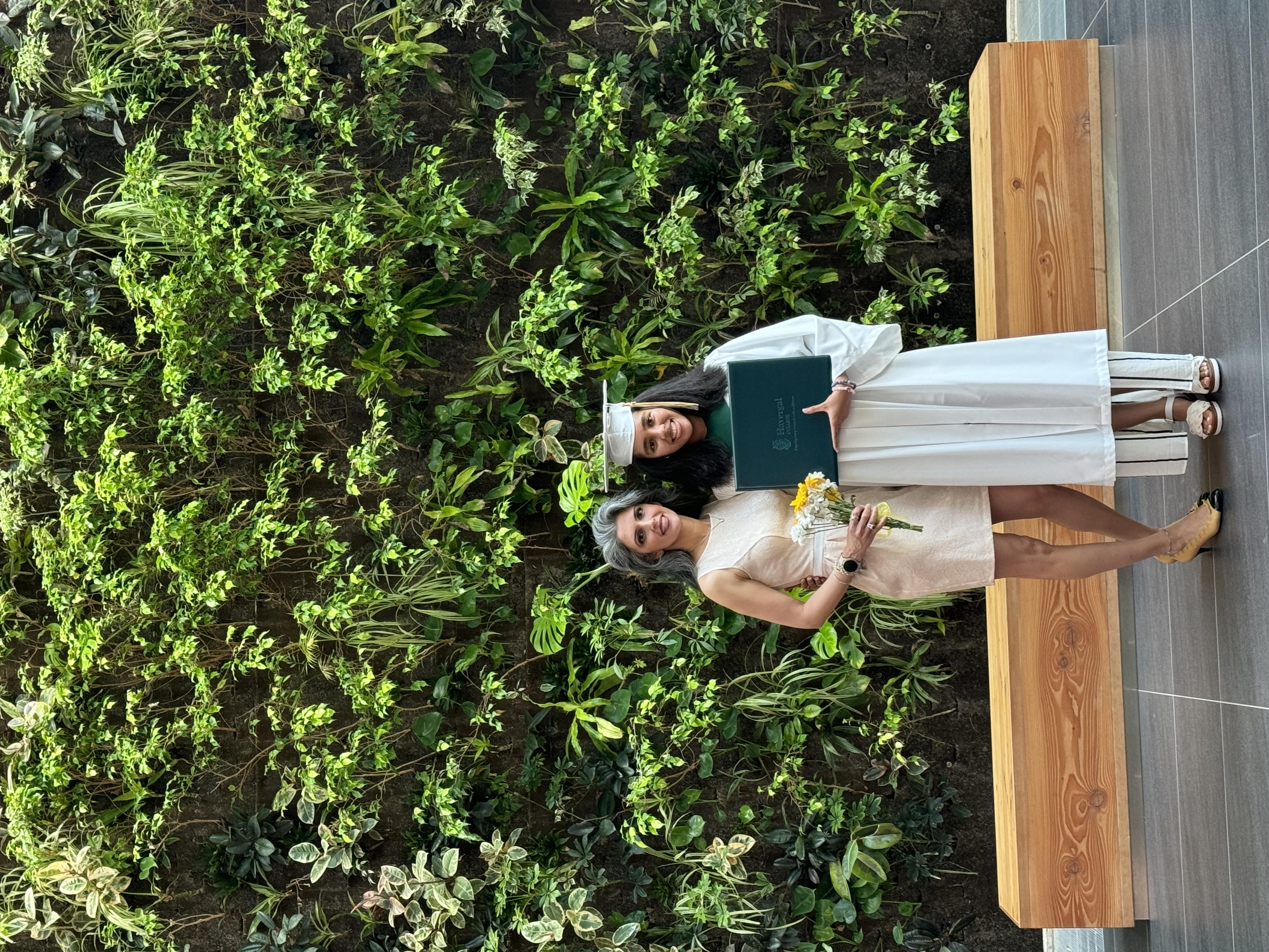 Chloe taking a picture with her mom at the bio wall on her high school graduation day.